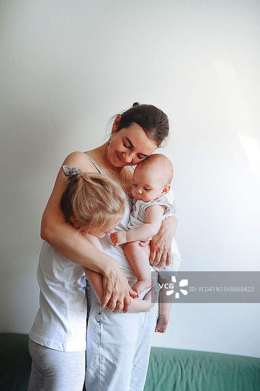 温馨的爱：中年母亲在家幸福地拥抱两个孩子图片素材