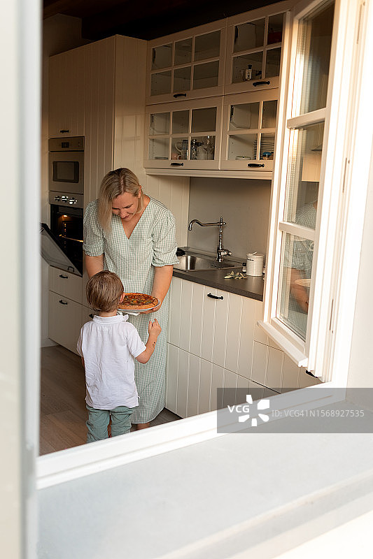 母亲给儿子一块刚做好的披萨图片素材