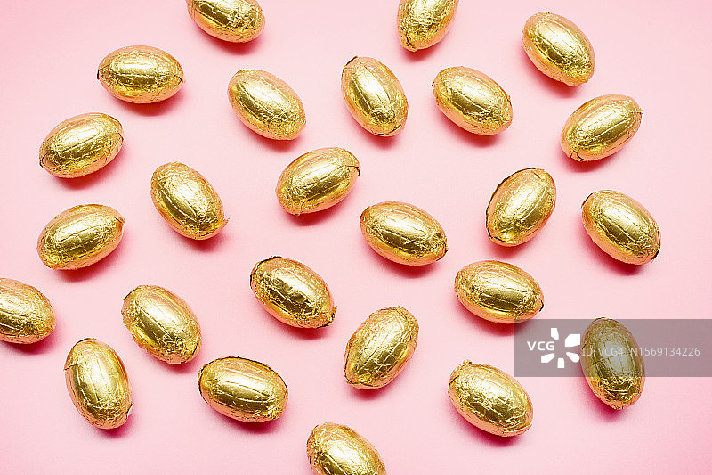 粉色背景上的金色巧克力复活节彩蛋高角度视图图片素材