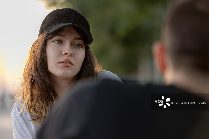 年轻夫妇坐在公园长椅上交谈图片素材