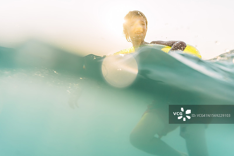 六岁男孩带着黄色游泳圈在日落时享受大海图片素材