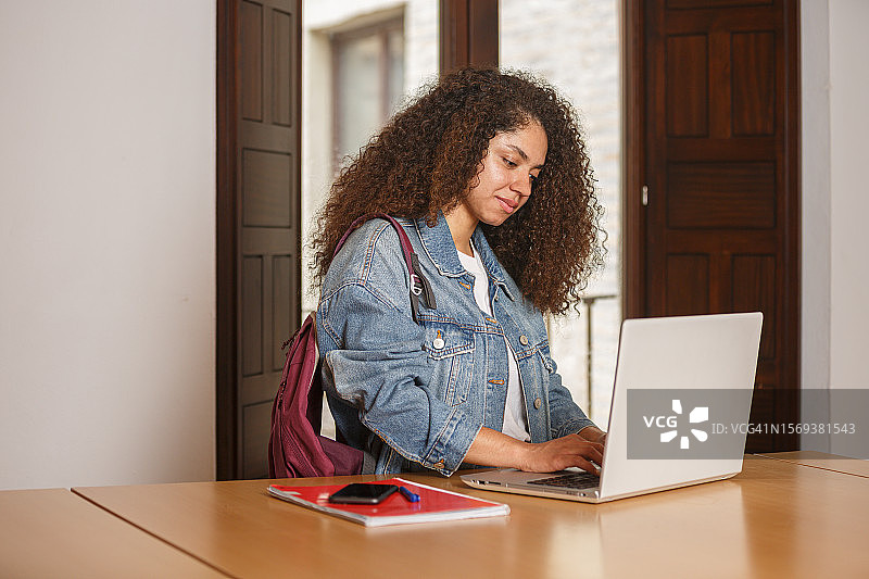 在图书馆用笔记本电脑工作的专注女士图片素材