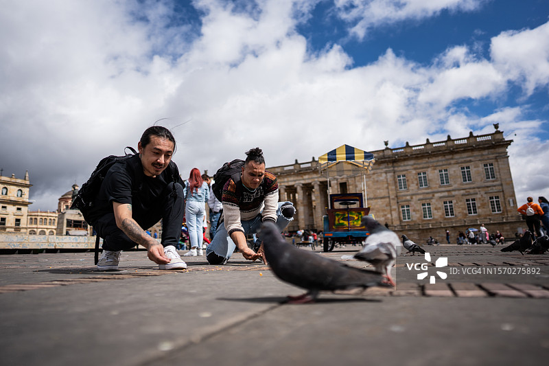 朋友们在哥伦比亚波哥大历史街区喂鸽子图片素材