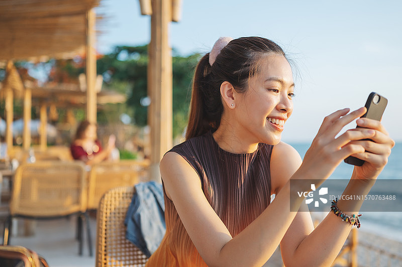 商务女性微笑旅行，享受周末假期，在智能手机和聊天机器人上工作，享受自由的生活方式图片素材
