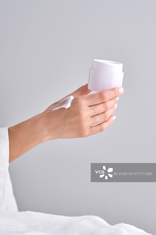 女人拿着一罐白色面霜图片素材