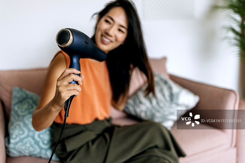 年轻女人在家吹干头发图片素材
