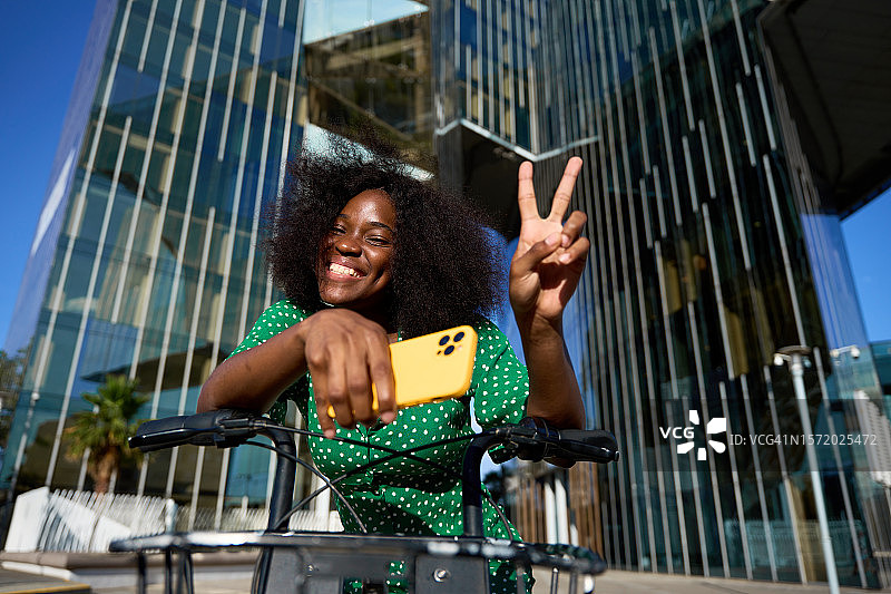在现代城市的夏日里做胜利手势的年轻黑人女子图片素材
