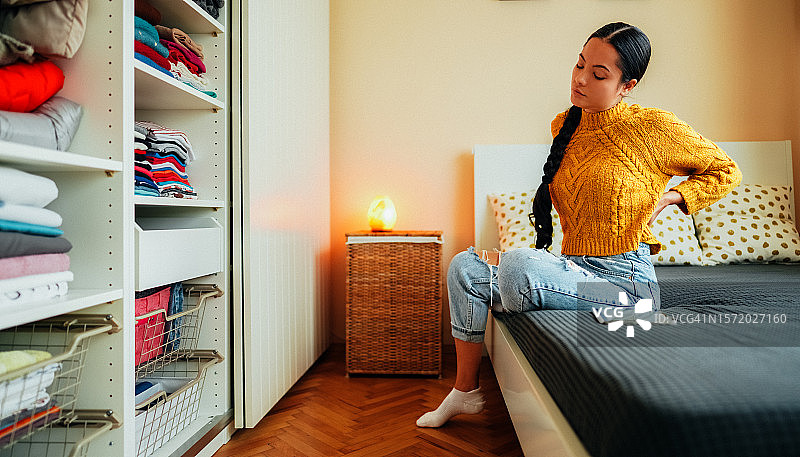 患有背痛待在家的女人图片素材