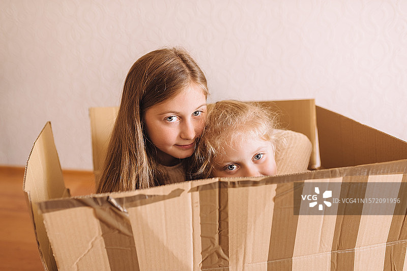 姐妹俩躲在大型纸板箱里图片素材