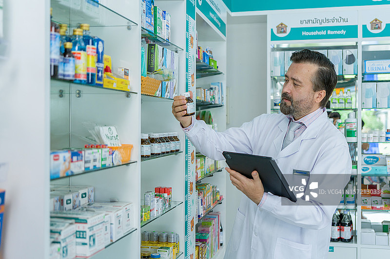 药剂师使用数字平板电脑进行医疗在线清单检查图片素材