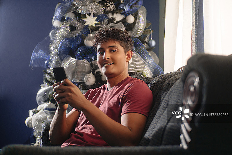 使用手机的西班牙裔青年男子，圣诞节概念图片素材