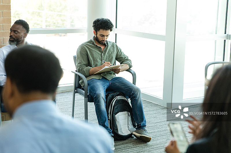 青年男子坐在银行大厅填写贷款申请图片素材