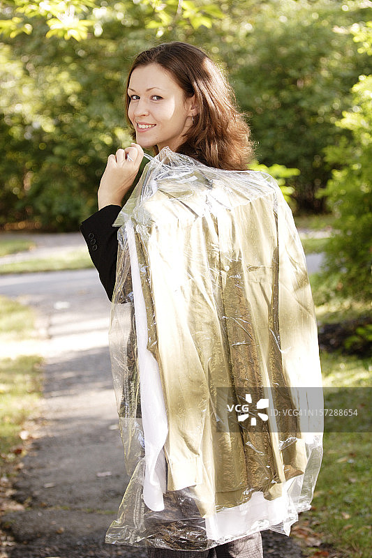 拿着干洗衣服的年轻女人图片素材