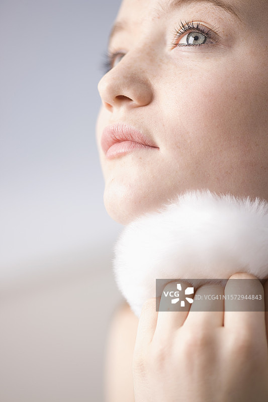 年轻女子用白色粉扑扑粉的特写图片素材