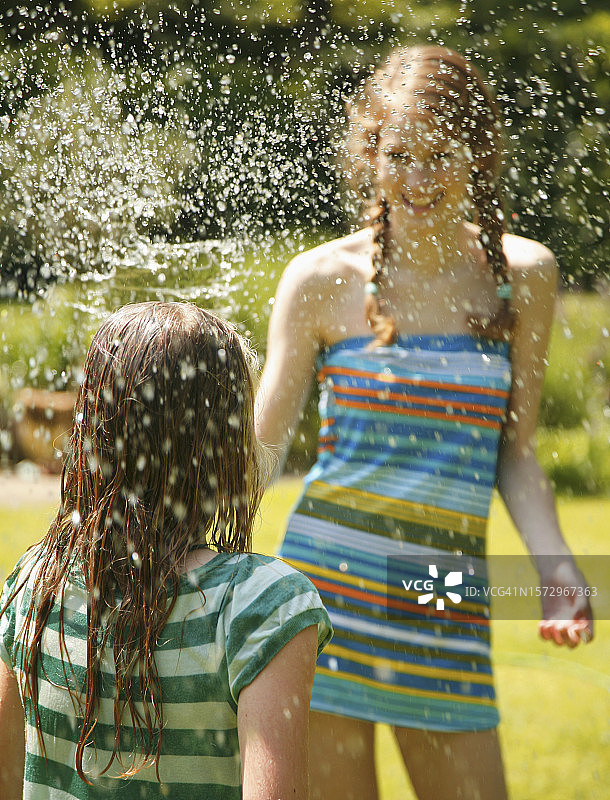 青少年用水喷洒女孩的肖像图片素材