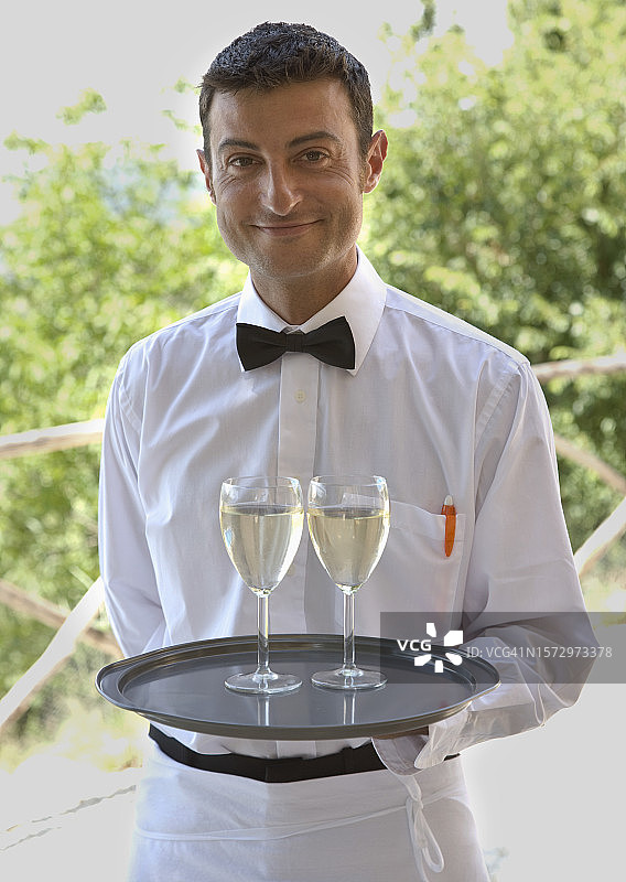 服务员站立并托着两杯白葡萄酒图片素材