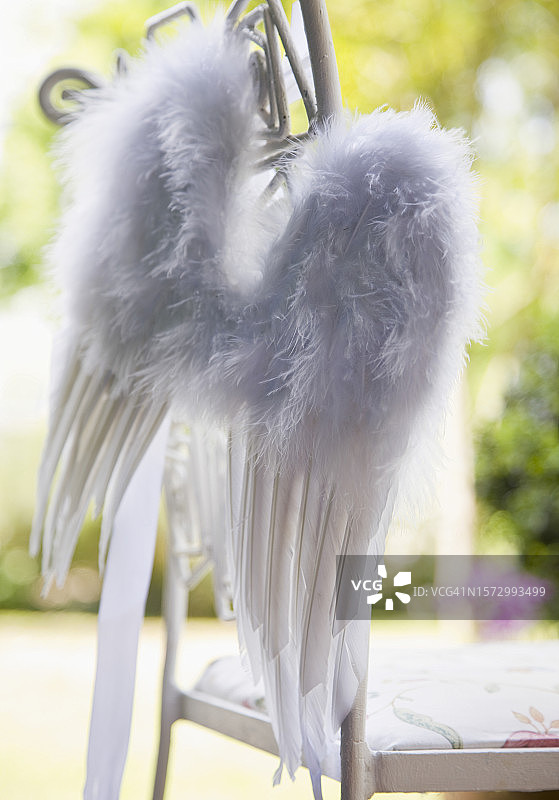 花园椅上悬挂的白色羽毛翅膀特写图片素材