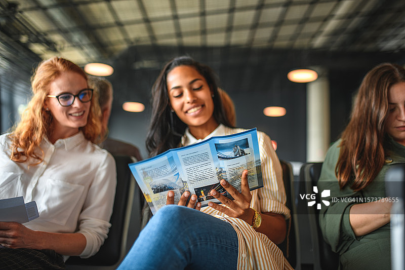 在机场查看目的地宣传单的女性朋友们图片素材