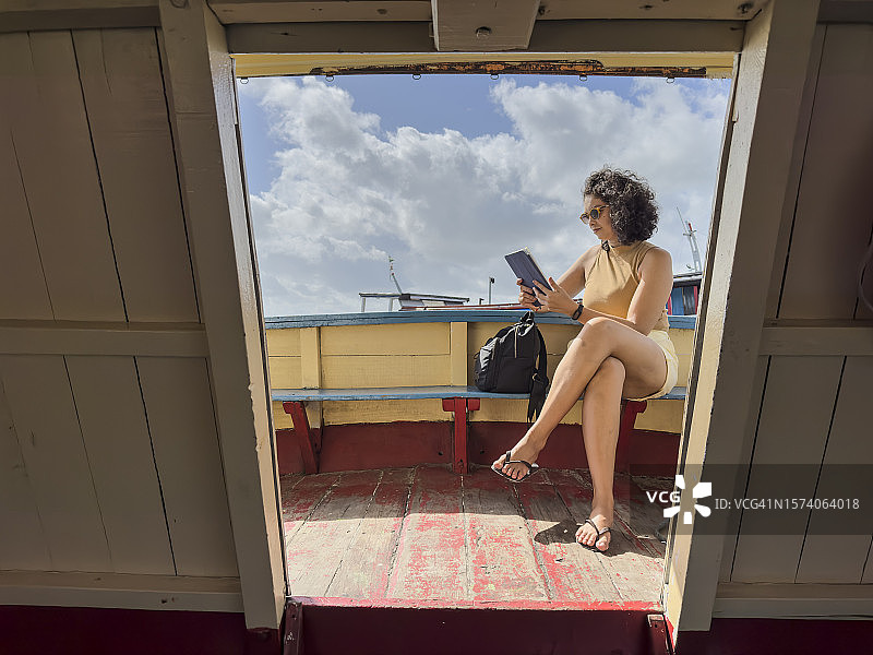 在船上使用平板电脑的微笑的拉丁女人图片素材
