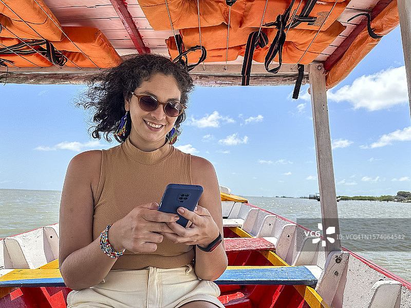 在船上使用手机的微笑拉丁女人图片素材