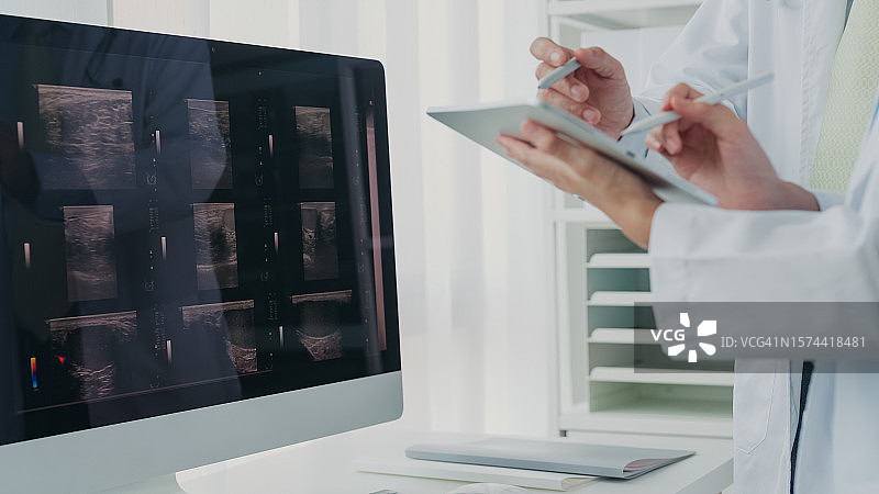 医疗团队的亚裔男女医生在医院的电脑上检查病人的X光片，讨论结果，医疗保健图片素材