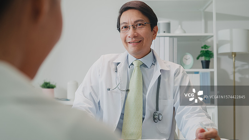 亚洲男医生在医院会诊时查看女患者的医疗结果图片素材