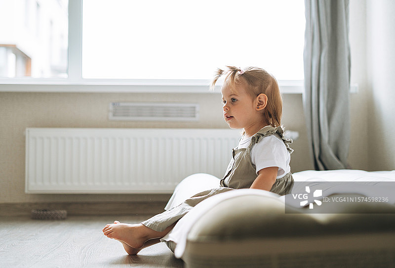 穿着家居服坐在床上，在家的可爱女宝宝，俄罗斯斯维尔德洛夫斯克州叶卡捷琳堡图片素材