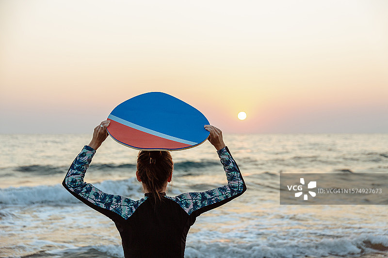 在海滩上手举滑板的年轻白人女子图片素材