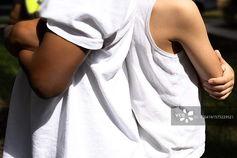 年轻的黑人男孩和年轻的多种族女孩背靠背，双臂交叉图片素材