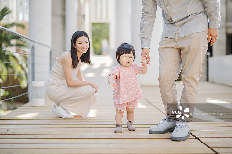 快乐的中国三口之家在户外享受夏日午后，迈出第一步图片素材