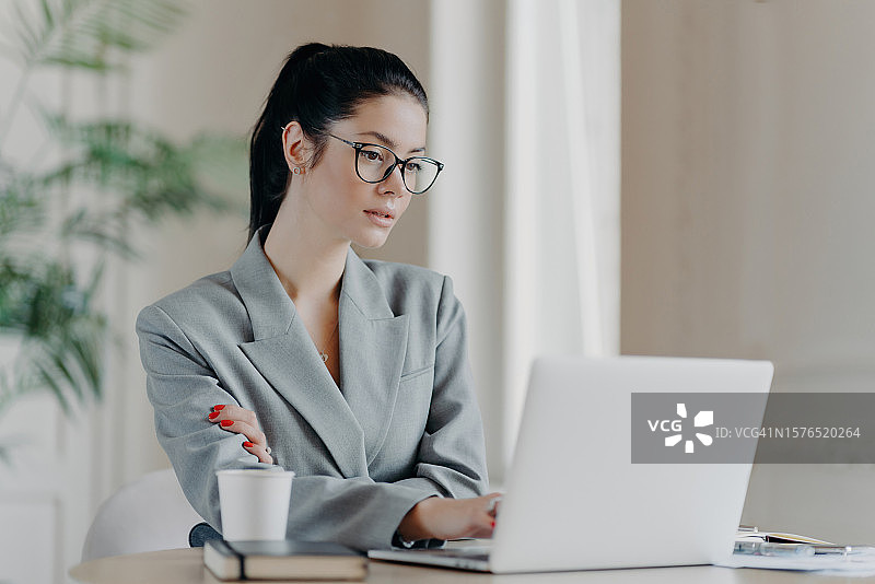 女商人使用笔记本电脑在办公室办公桌前工作图片素材