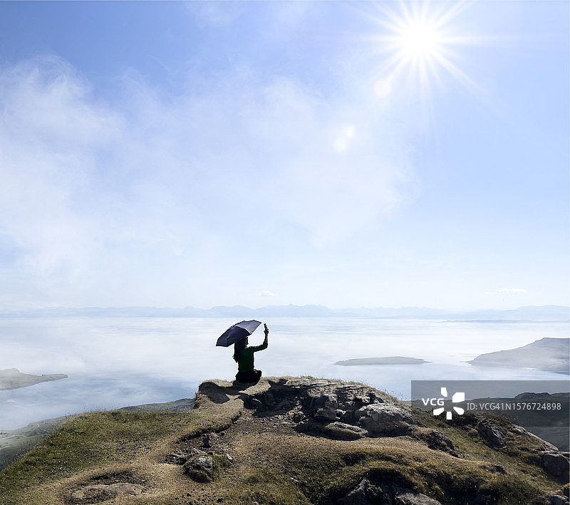 在山顶自拍的撑伞女人图片素材
