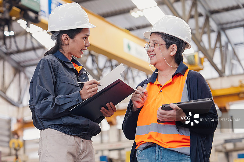 快乐的女工程师在工厂里愉快讨论图片素材