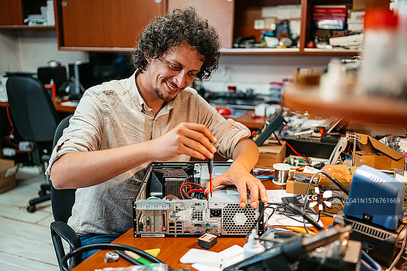 用螺丝刀修理台式电脑的年轻男人图片素材