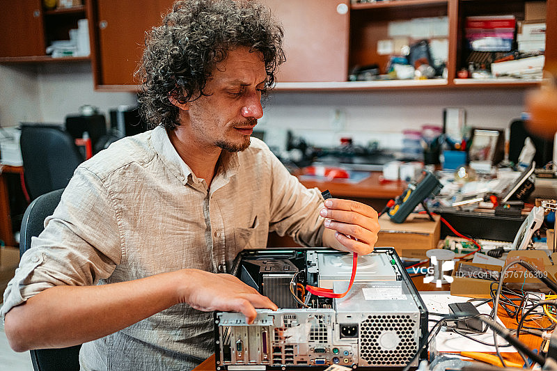 年轻人将电缆连接到计算机单元图片素材