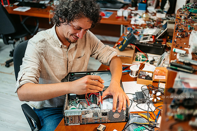 用螺丝刀修理台式电脑的年轻男人图片素材