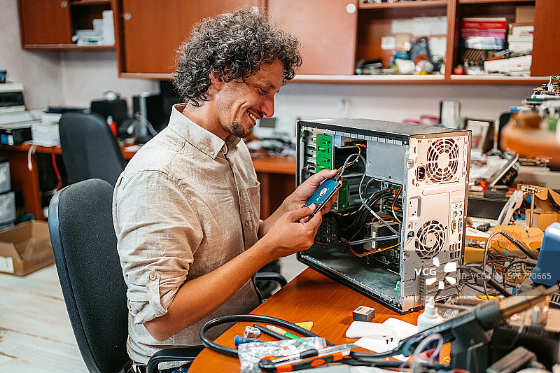 年轻男人在工作室组装台式电脑图片素材