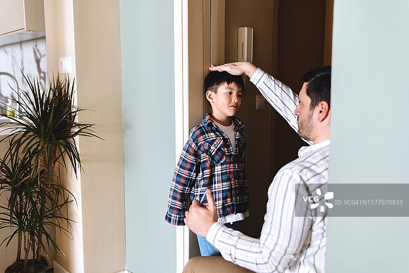 慈爱的父亲为儿子量身高特写图片素材