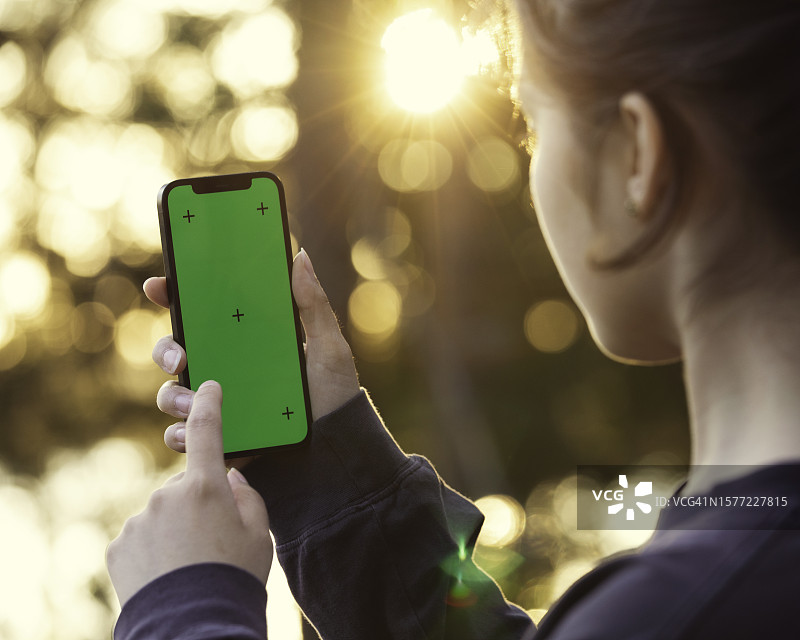 阳光下使用手机的年轻女人图片素材