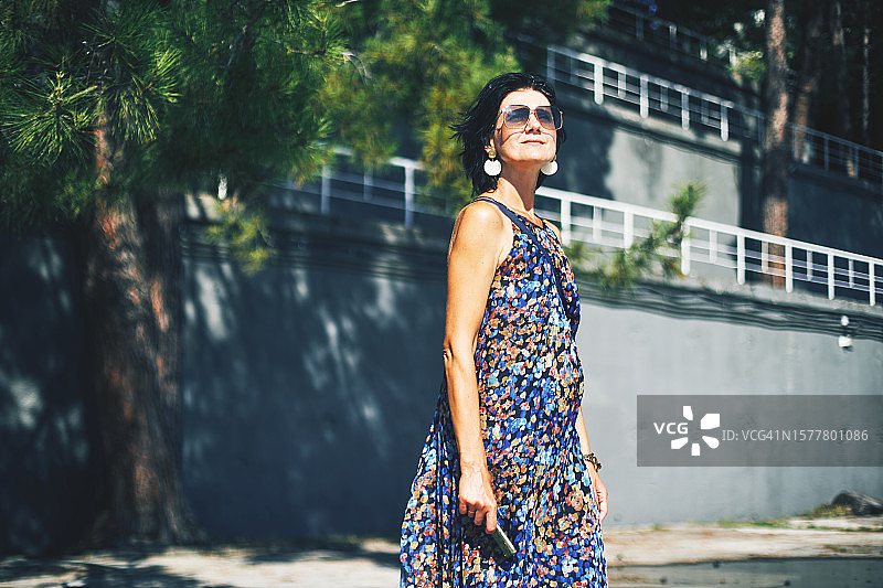 快乐的女人穿着时髦的衣服站在街上图片素材