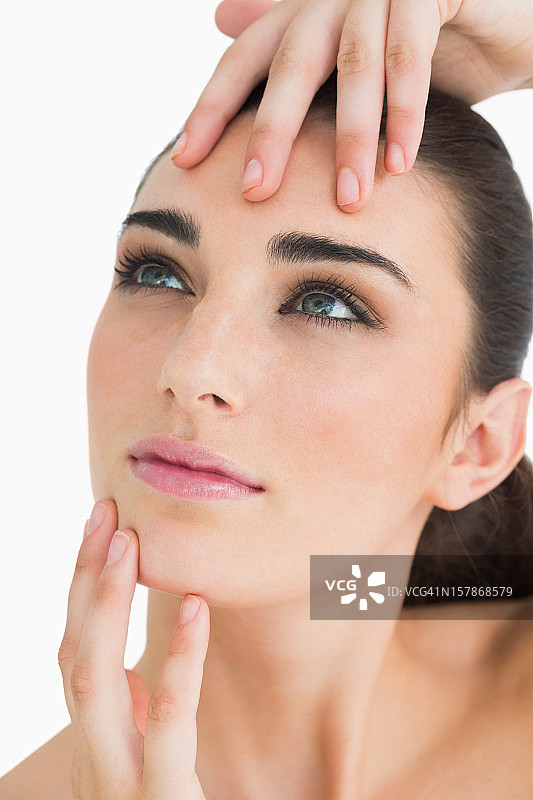 触摸脸部时抬头的女人图片素材