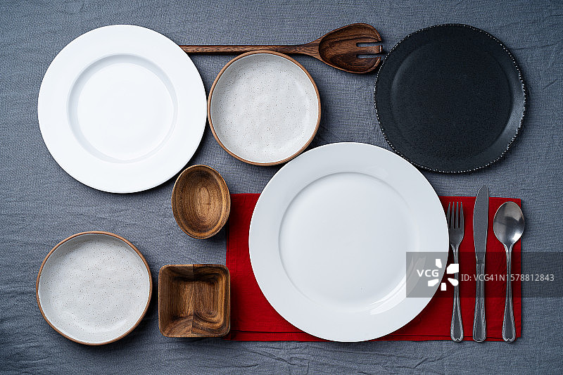 摆放整齐的白色陶瓷餐具和红色餐巾（灰色亚麻桌布背景）图片素材