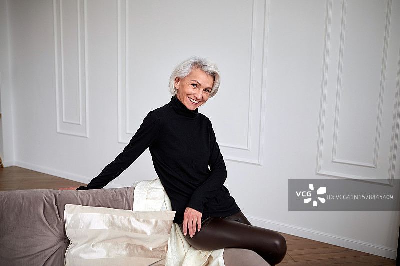 客厅沙发上时尚微笑的中年妇女图片素材