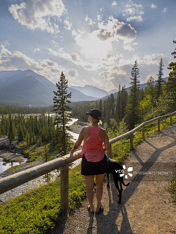 女人和狗在河边的路上徒步旅行图片素材
