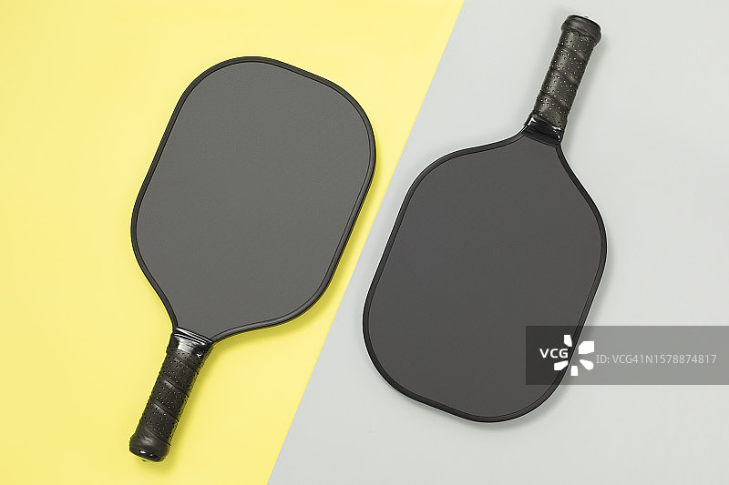 黄色和灰色背景上的两个匹克球拍顶视图图片素材