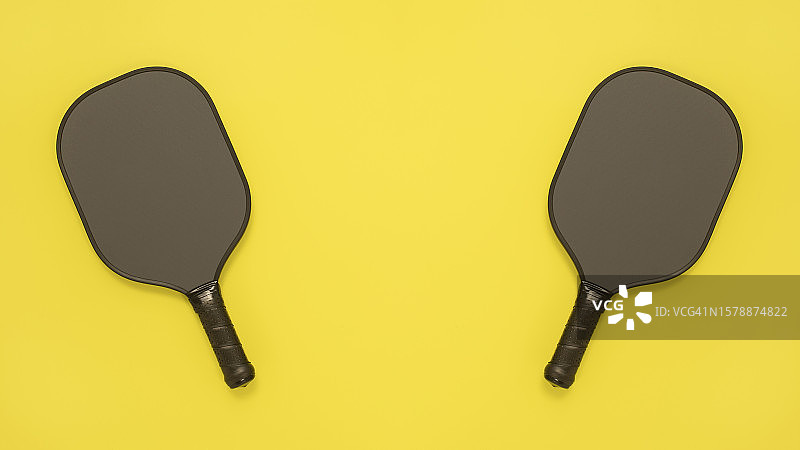 黄色背景上的两个匹克球拍俯视图图片素材