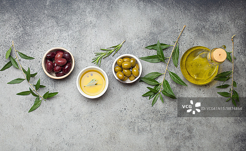 灰色背景上绿色和棕色橄榄与原始橄榄油的构图，有复制空间图片素材