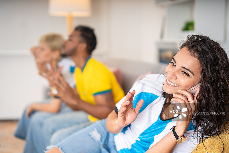 当朋友们观看足球比赛时，女人正在打电话图片素材