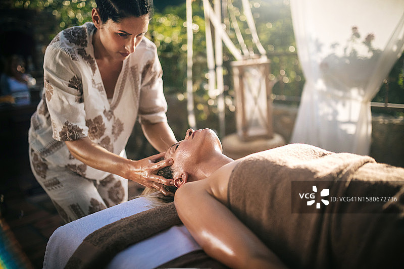 在水疗沙龙接受泰式头部按摩的漂亮女人图片素材