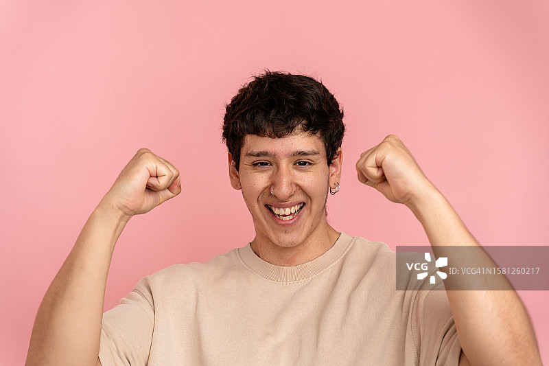 在粉色背景下庆祝好消息的年轻男子肖像图片素材